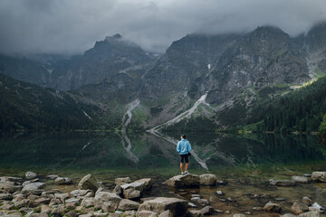 Man standing on rocks by Morskie Oko lake in Tatra mountains, Poland © WellStock