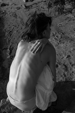 naked woman sitting on the sand