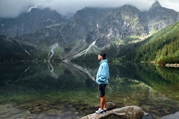 Man contemplating Morskie Oko lake and Tatra mountains reflection in spring © WellStock