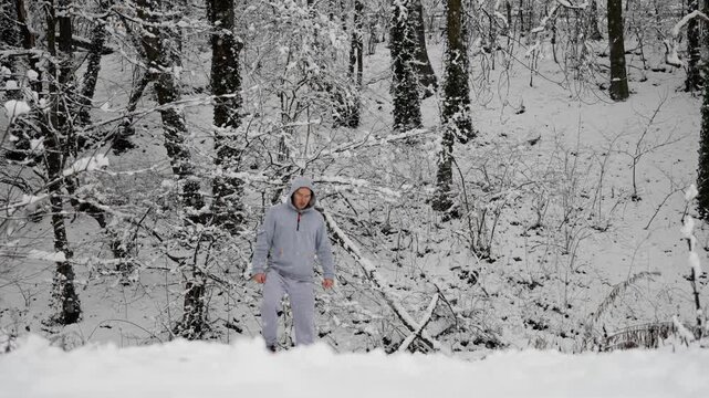 Calm Man In Snow Forest Warms Up. Focused Individual In Winter Woods Readying For Exercise. Quietly Resilient Man In Snowy Woods Prepares Mentally And Physically For Training Session