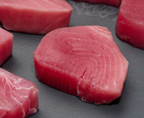 Raw tuna pieces on a black board, snack