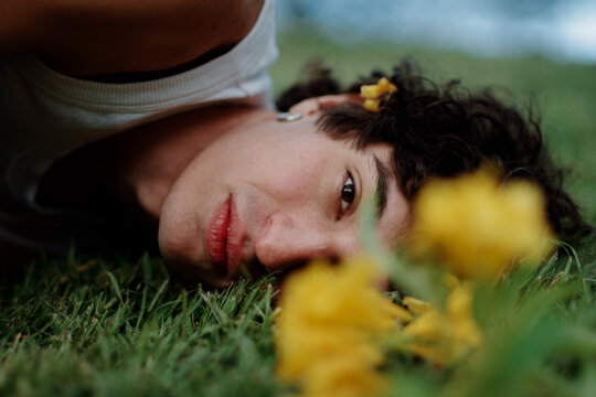 Young Person Lying on Grass With Flowers in Bright Outdoor Setting