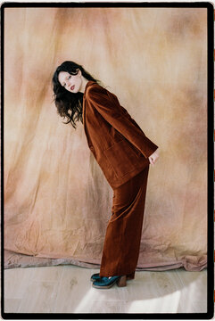 Woman in rust velvet suit bending forward