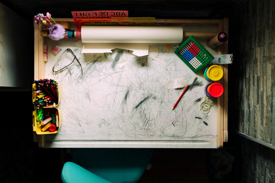 Kids messy desk doodled with pencil 