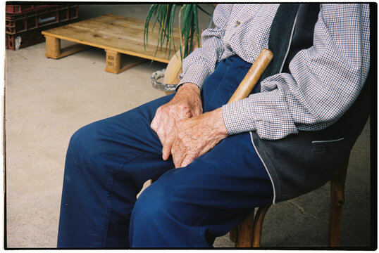 Film photo of hands on knees with a cane in a cozy spot
