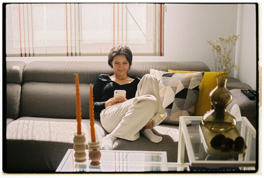 Young Woman Relaxing and Using Smartphone in Cozy Living Room
