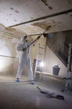 Worker Removes Old Paint From Ceiling in a Renovation Project