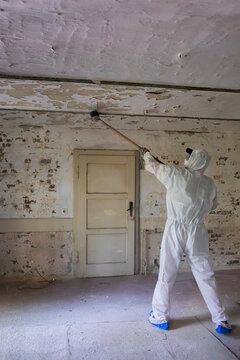 Worker Removes Old Paint From Ceiling in Abandoned Building