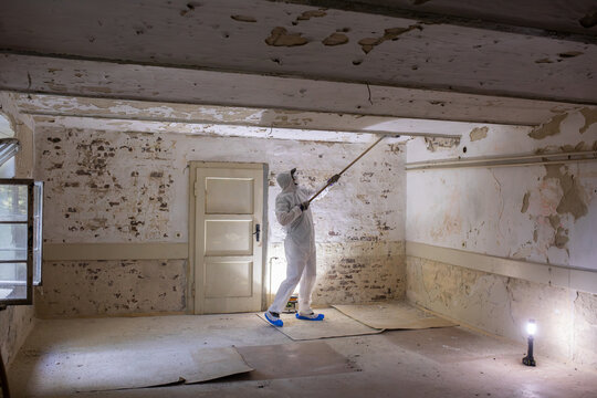 Worker Cleaning and Restoring an Old Room With Peeling Walls