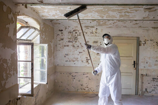 Worker Removes Old Paint From Ceiling in an Abandoned Building