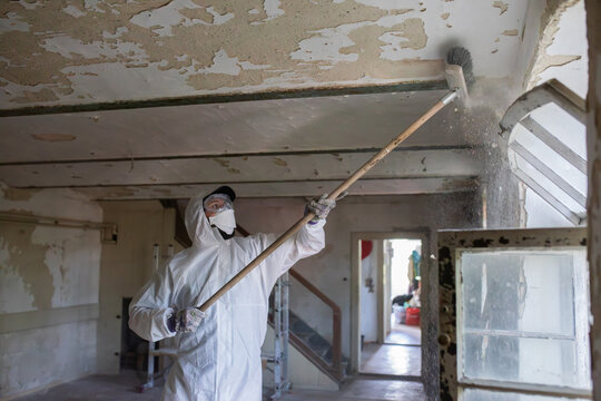 Worker in Protective Suit Renovating an Old Abandoned Building