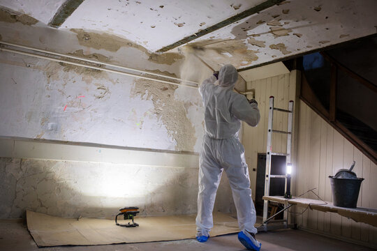 Worker in Protective Suit Renovating an Old Abandoned Building