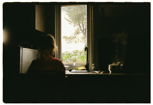 Girl with tablet standing in kitchen with steaming pot