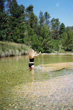 Film photo of a woman playing in clear water at a tranquil river