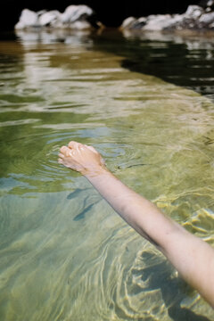 Film photo of hand reaching into clear water at a serene location