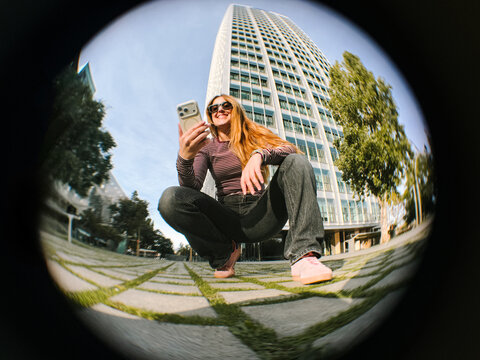 Woman smiling crouched with phone