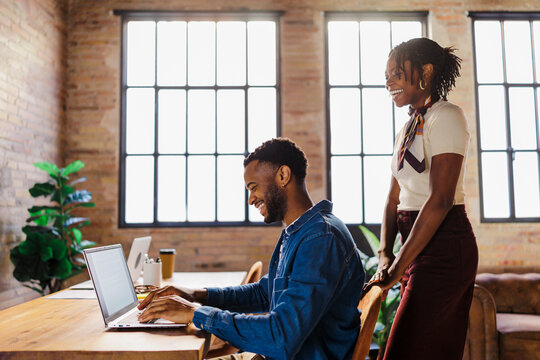 Colleagues collaborating on laptop in modern office space
