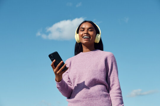 Woman smiling while using smartphone outdoors