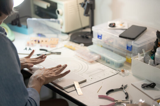 Asian woman working on handmade clay jewelry craft at home workspace
