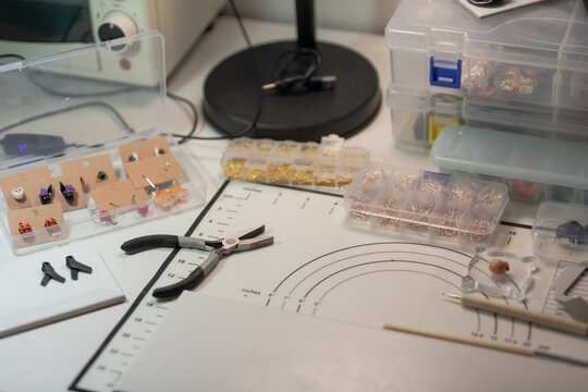 Asian woman's desk for working on handmade clay jewelry craft 