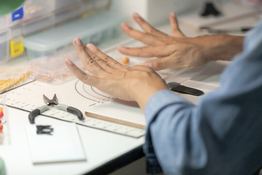 Asian woman working on handmade clay jewelry craft at home workspace