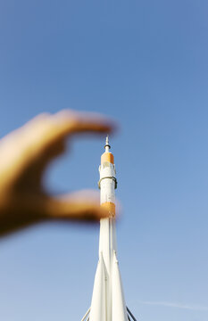 Hand Appears to Hold Rocket Engine Against Clear Blue Sky
