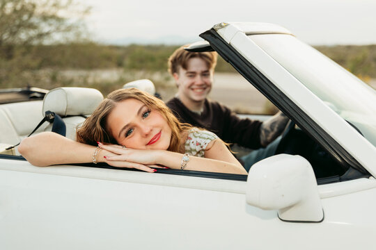 Young woman resting her head on side of convertible