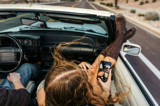 Teenage girl on phone in convertible 