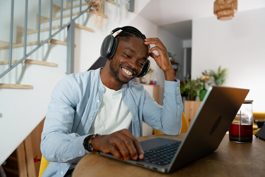 Smiling man wearing headphones remote working with laptop