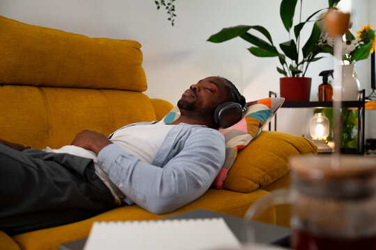 Man relaxing on sofa enjoying music with headphones