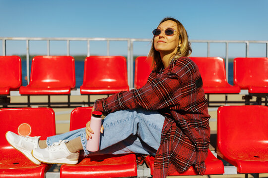 Relaxing in the Sun on Red Bleachers by the Sea in Warm Weather