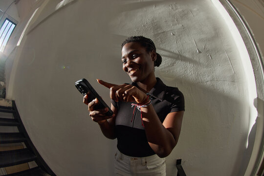 Young woman smiles while using smartphone in a bright room