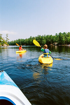 Children kayaking together on a lake in Maine