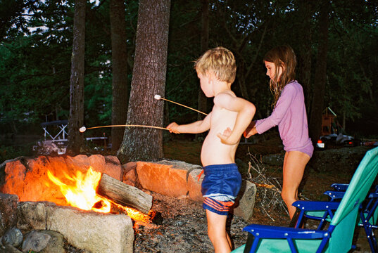 Kids toast marshmallows over a campfire