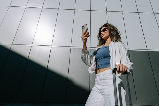 Woman with smartphone and suitcase 