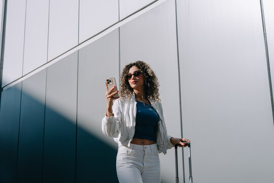 Woman with smartphone and suitcase 