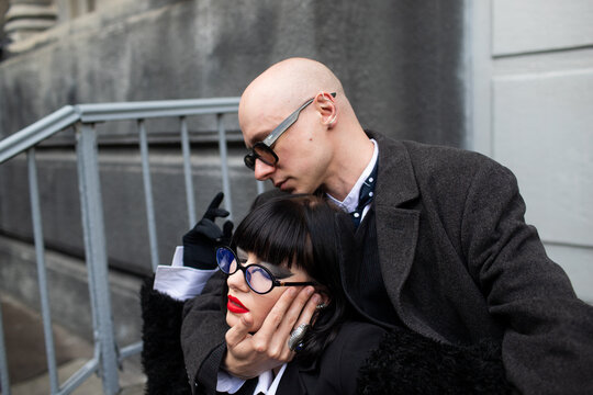 A man and a woman are sitting on the steps outside.
