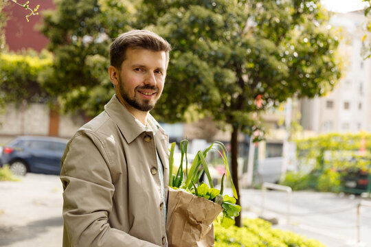 Portrait of a young man with a paper bag of vegetables