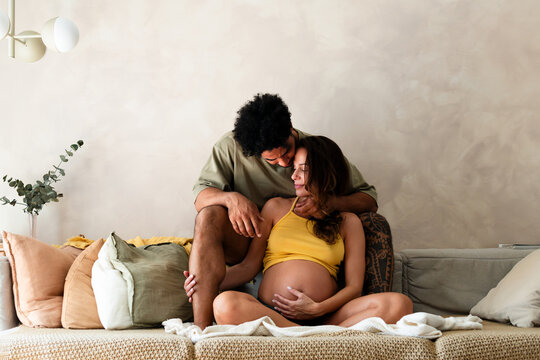 Expecting Partners Sharing Affectionate Embrace on Couch