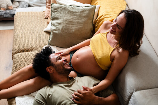 Pregnant couple laughing on sofa