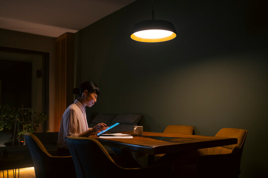 Woman working late night at home using tablet