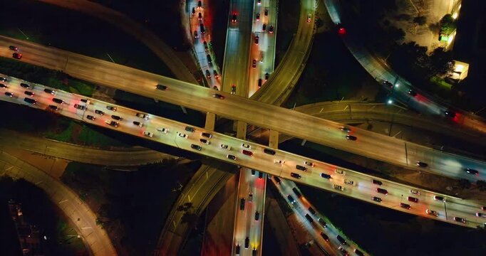 Well-lit highways of multi-level interchange are filled with cars. Rising over the busy intersection of Los Angeles, California, USA at night.