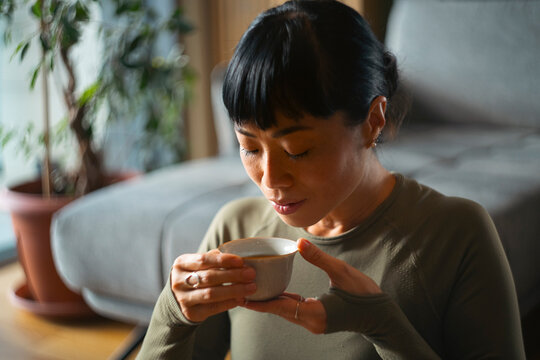 Asian woman enjoying relaxing mindful tea time at home