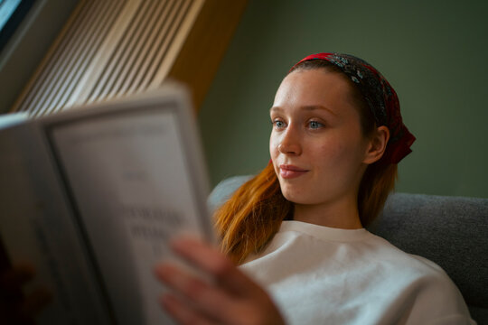 Young redhead woman relaxing reading a book