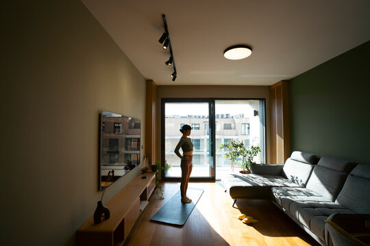 Woman practicing yoga in sunny modern living room
