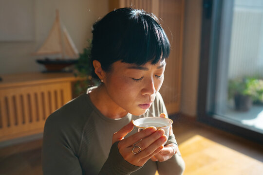 Woman mindfully blowing on hot tea cup
