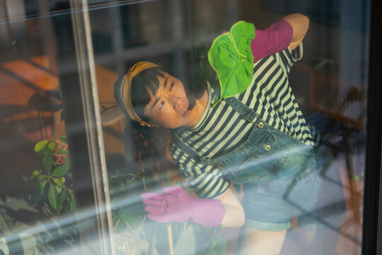 Woman making effort cleaning window during spring housework
