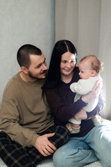 Fototapeta premium Young parents lovingly holding their newborn baby, sharing a tender moment at home