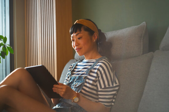Young asian woman relaxing at home using digital tablet
