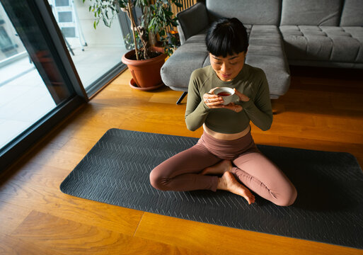Young woman enjoying tea after yoga practice at home